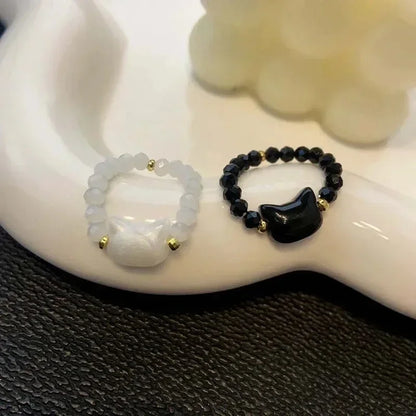 Two white and black beaded Cat Charm Rings on a curved white dish | Oria Jewel