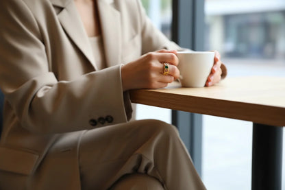 Cozy café moment holding a cup, showcasing a Colorful stone band ring with vibrant bezel-set stones | OriaJewel