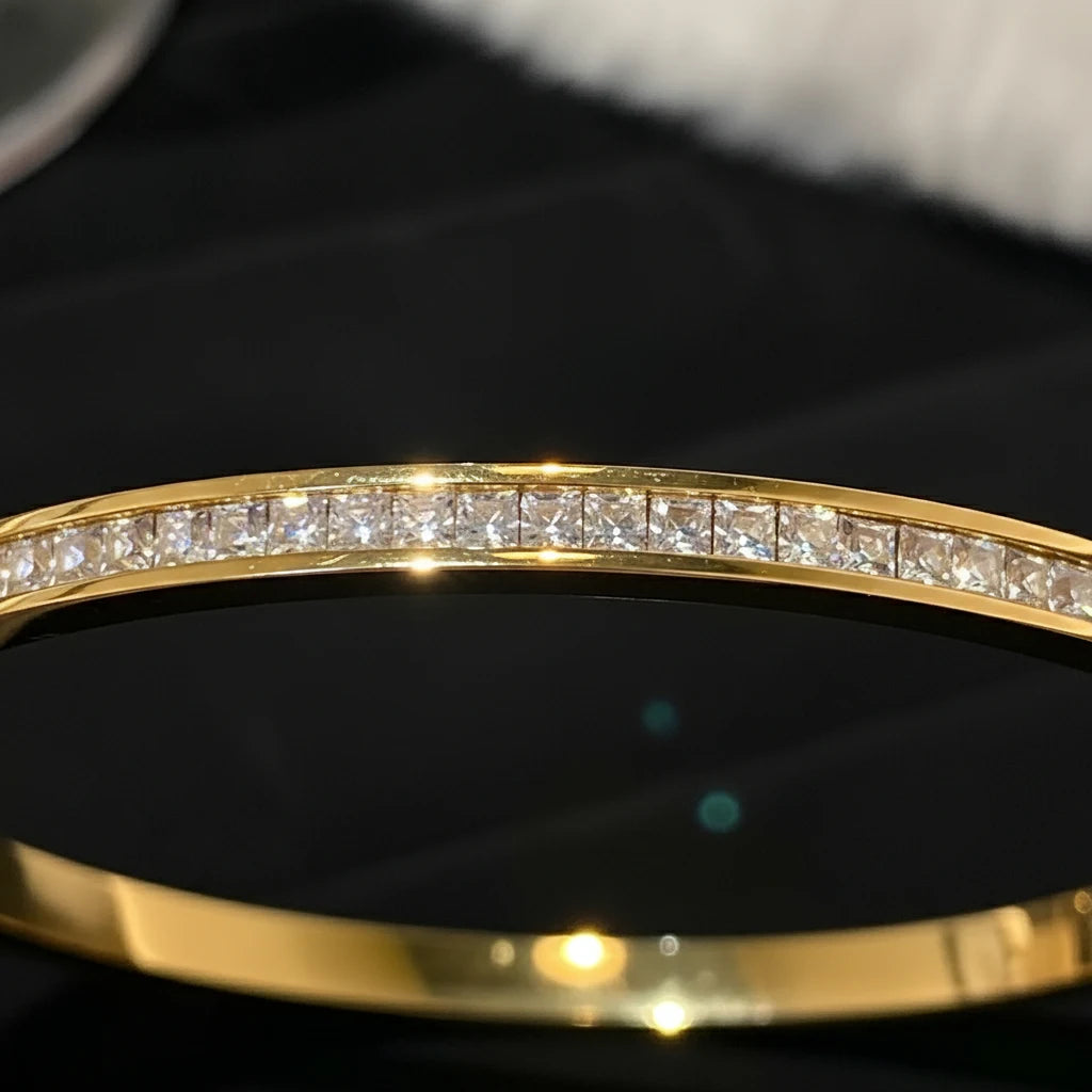 Elegant close-up of a Crystal Line Gold Bangle with a row of square-cut crystals sparkling along the top edge against a dark background, highlighting the sleek polished gold finish and refined minimalist design | Oria Jewel