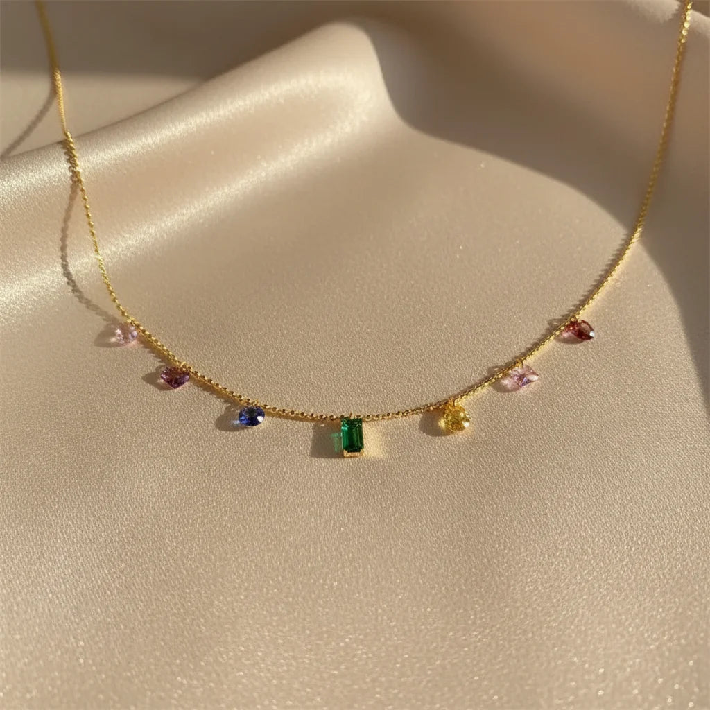 Close-up of Elegant Zircon Necklace on satin fabric — gold chain with multicolor zircon charms sparkling under sunlight | Oria Jewel