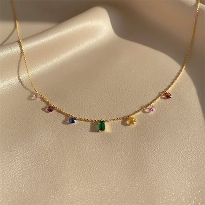 Close-up of Elegant Zircon Necklace on satin fabric — gold chain with multicolor zircon charms sparkling under sunlight | Oria Jewel