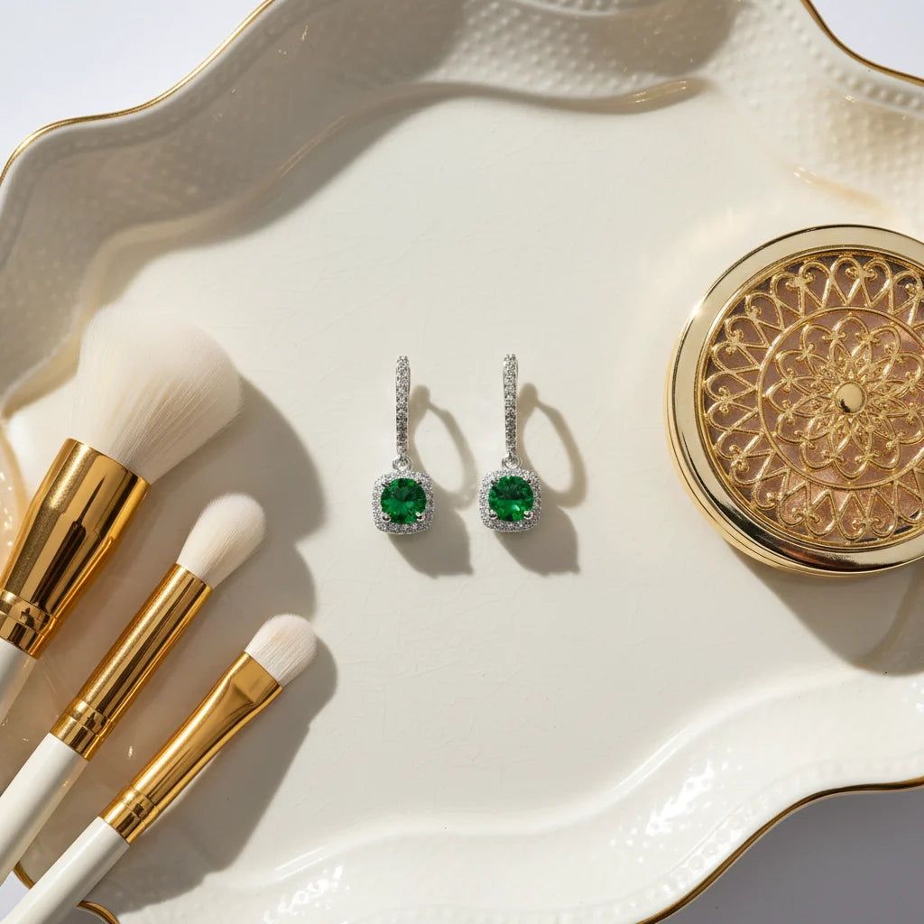 Emerald Green Drop Huggie Earrings flat lay on ivory tray with makeup brushes | OriaJewel