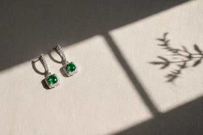 Emerald Green Drop Huggie Earrings on textured fabric with natural shadow | OriaJewel