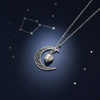 Glowing Moon Locket necklace laid on deep blue starry background with constellation pattern, emphasizing celestial theme | Oria Jewel