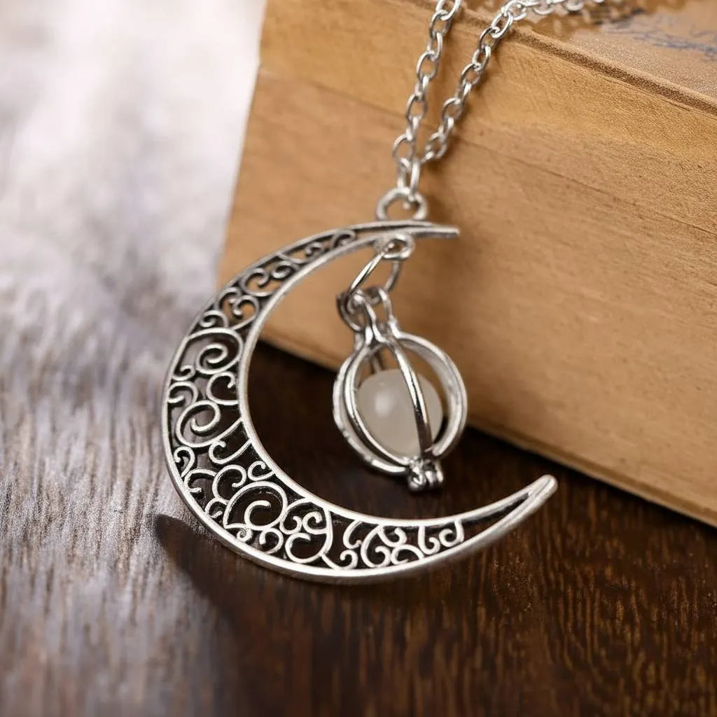 Vintage-style Glowing Moon Locket with filigree crescent and milky orb displayed on wooden box over rustic wooden surface | Oria Jewel
