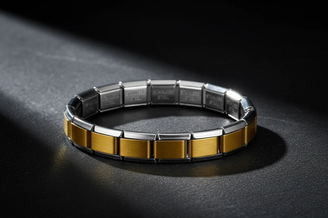 Dramatic studio close-up of Gold Center Stainless Steel Stretch Bracelets resting in a circular shape on a dark textured surface, with a spotlight highlighting the contrast between the brushed gold center links and polished silver edges | Oria Jewel