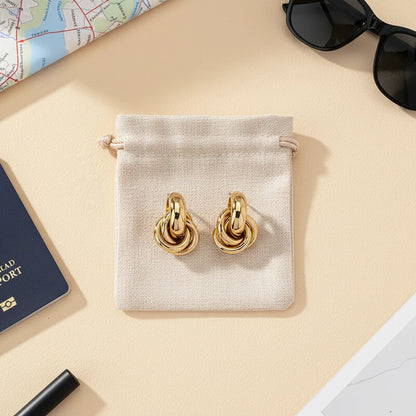 Gold Chunky Knot Stud Earrings flat lay on pouch with travel accessories | OriaJewel