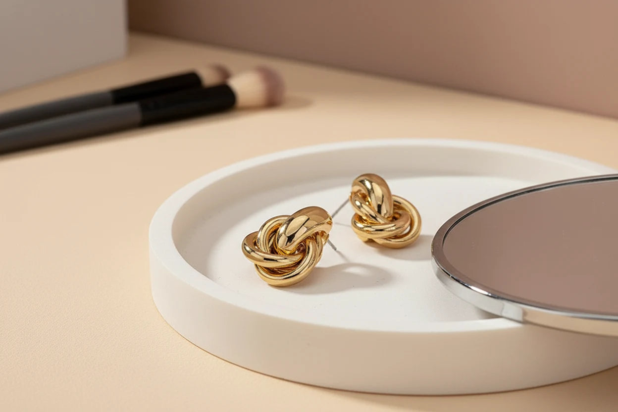 Gold Chunky Knot Stud Earrings on white tray with mirror and brushes | OriaJewel