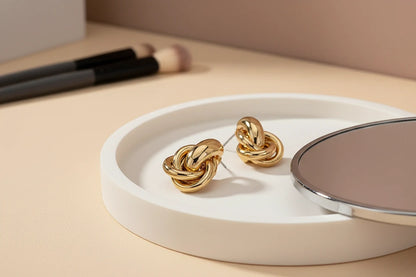 Gold Chunky Knot Stud Earrings on white tray with mirror and brushes | OriaJewel