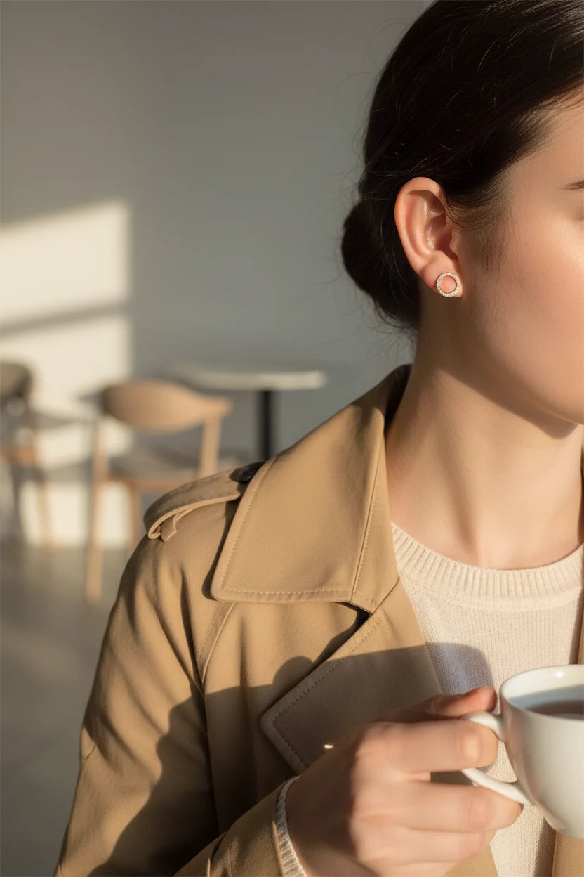 Gold Circle Stud Earrings worn with trench coat holding coffee close-up | OriaJewel