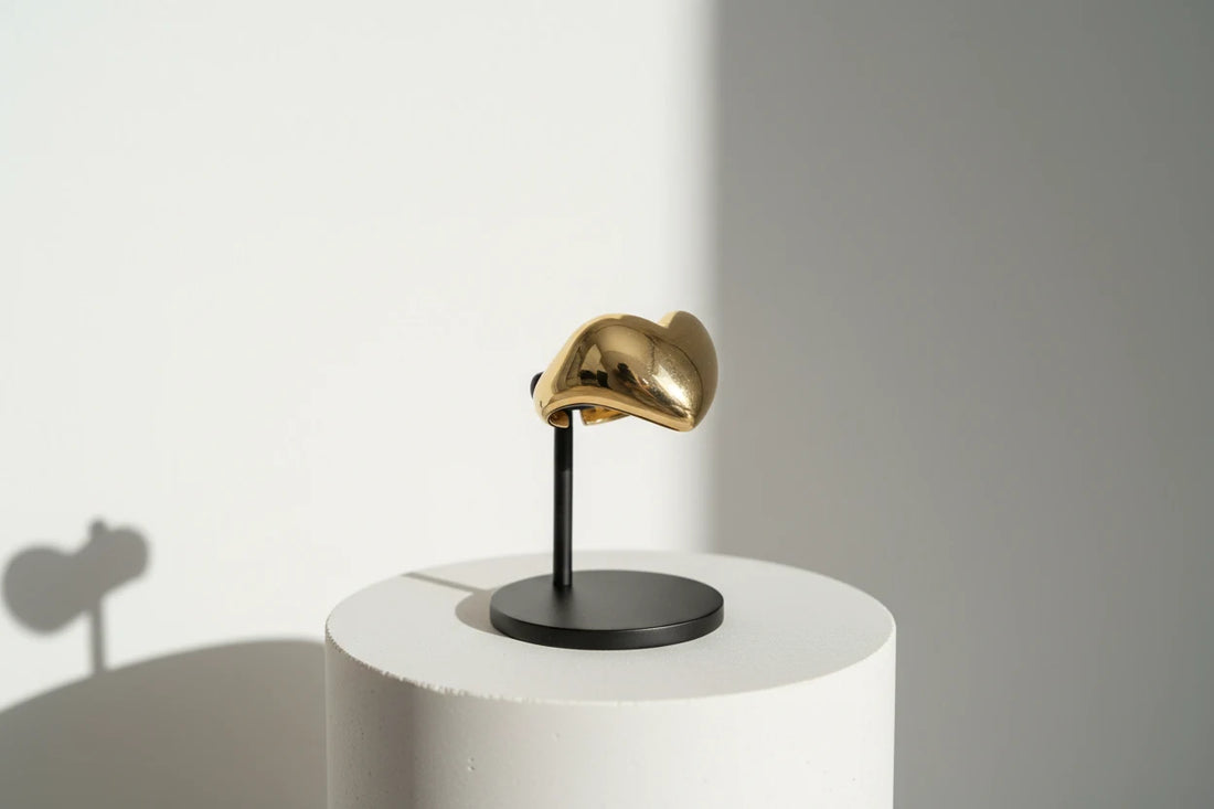 Gold Heart Open Ring displayed side-view on a minimal black jewelry stand over a white pedestal, highlighting the glossy heart dome and open-ended band design. | OriaJewel