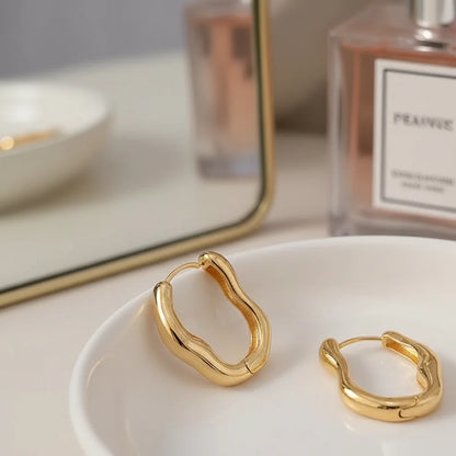 Gold Huggie Hoop Earrings close-up on white dish with vanity mirror and perfume | OriaJewel