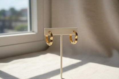 Gold Huggie Hoop Earrings on display stand by window light | OriaJewel