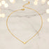 Close-up of Gold Love Pendant Necklace on slim gold chain over cream ribbed turtleneck top in warm light | Oria Jewel