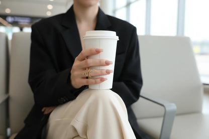 gold Pavé snake wrap ring on finger holding a white to-go cup in a modern airport lounge | OriaJewel