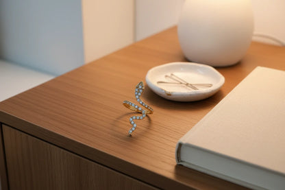 gold Pavé snake wrap ring displayed on a wooden nightstand beside a lamp and jewelry dish | OriaJewel