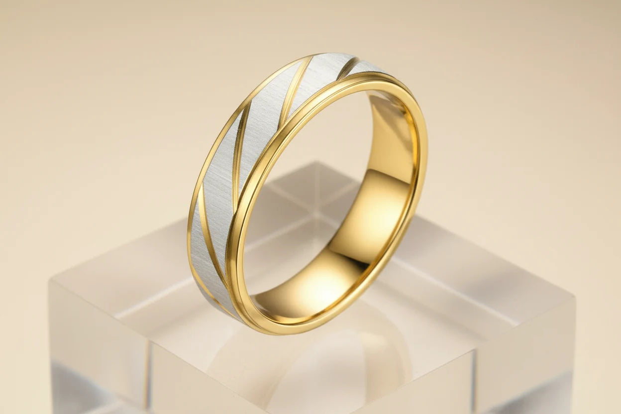 Studio hero shot of a Gold Silver Two Tone Band Ring on a clear acrylic block, brushed silver center panel with diagonal gold lines, beige gradient background | OriaJewel
