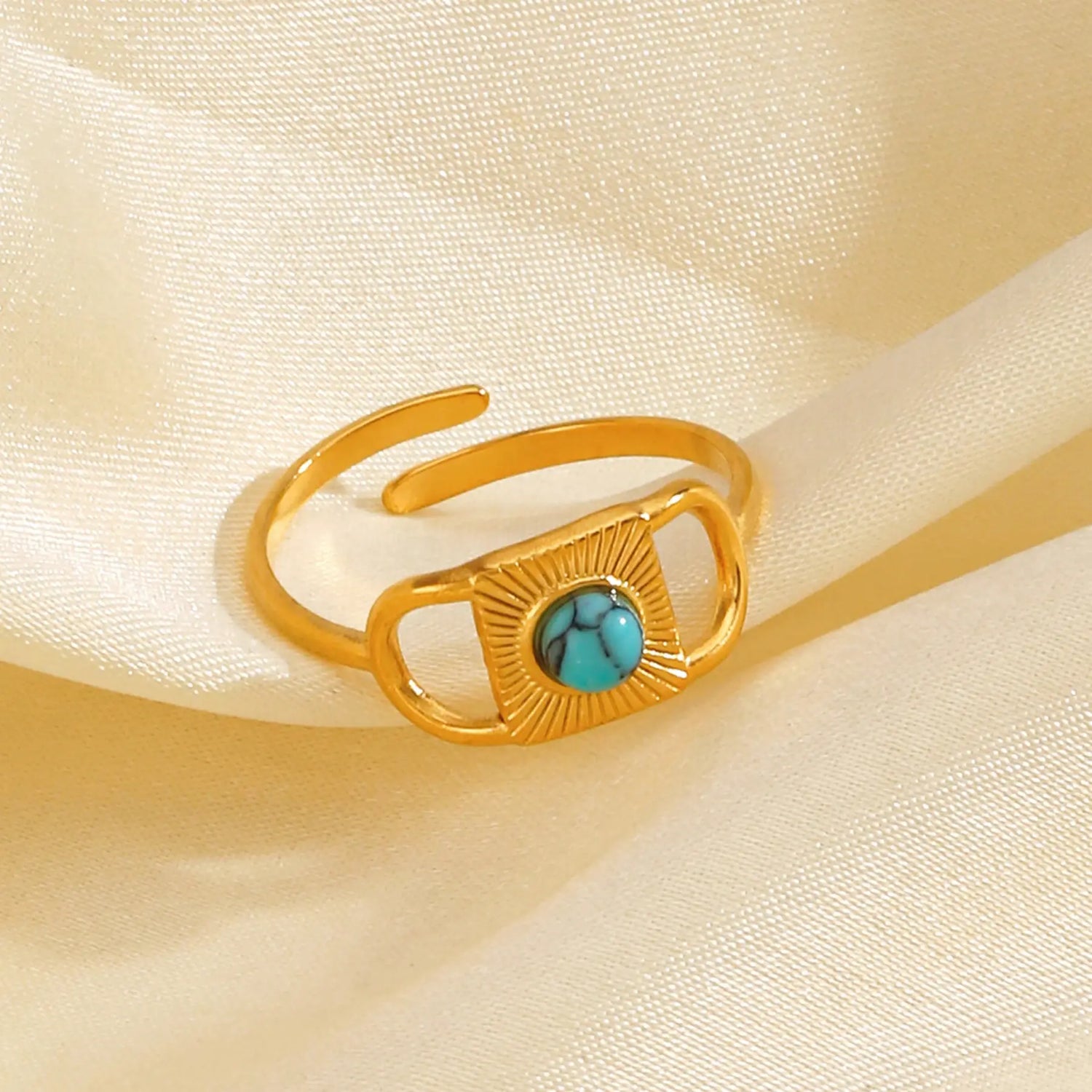 Gold Turquoise Adjustable Open Ring close-up on soft cream satin fabric, featuring an open adjustable gold band with a rectangular sunburst plate and a round turquoise center stone | OriaJewel