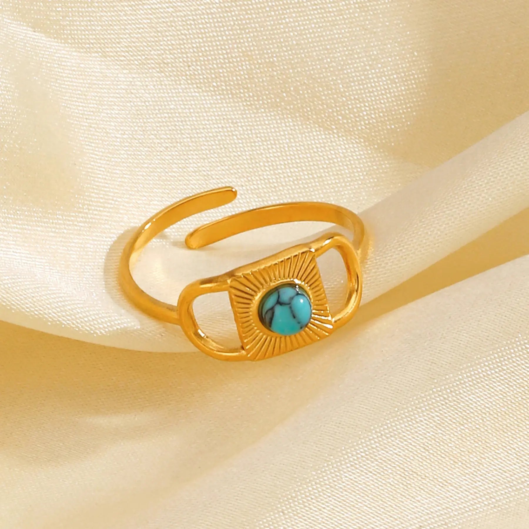 Gold Turquoise Adjustable Open Ring close-up on soft cream satin fabric, featuring an open adjustable gold band with a rectangular sunburst plate and a round turquoise center stone | OriaJewel