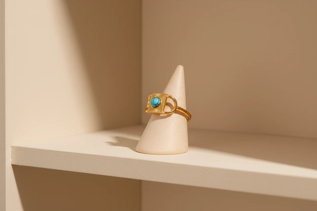 Gold Turquoise Adjustable Open Ring displayed on a small cone stand in a warm beige studio corner, highlighting the ring’s adjustable open back and turquoise sunburst statement design | OriaJewel