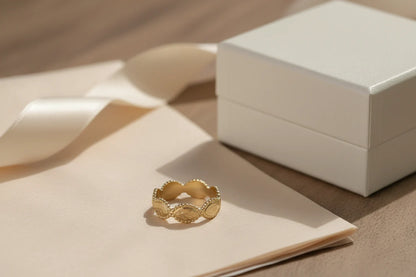 Gold beaded marquise ring on a cream envelope with a satin ribbon and a small white jewelry box, elegant gift-style composition with warm highlights | OriaJewel