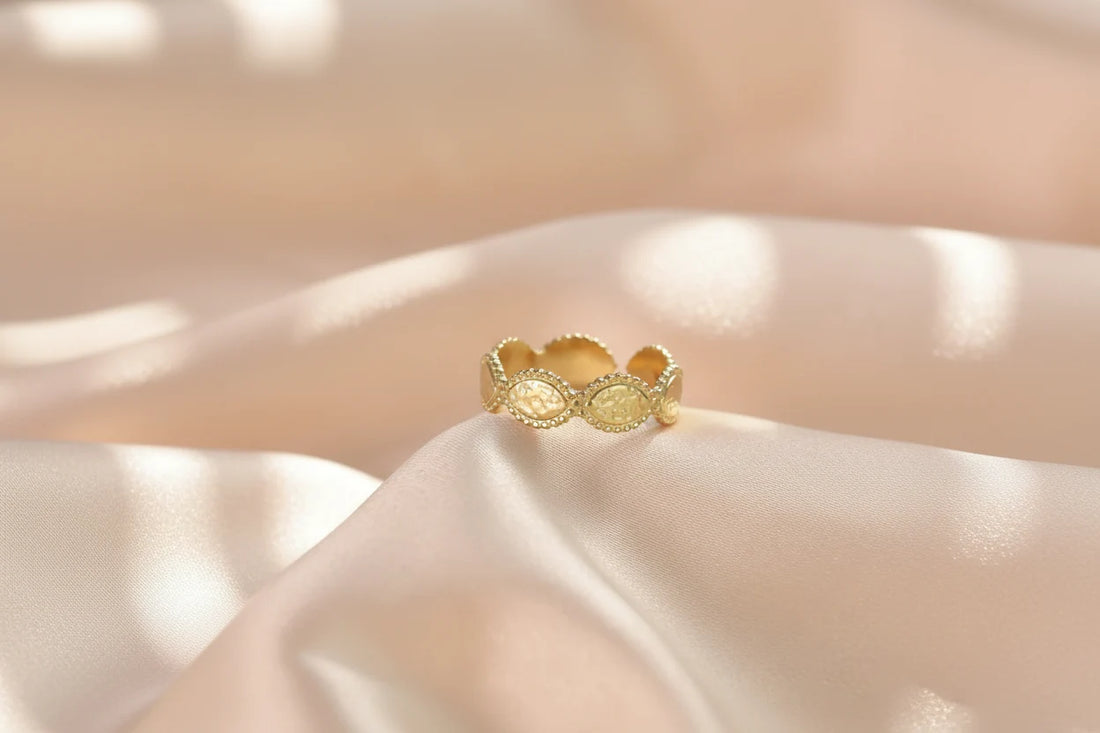 Gold beaded marquise ring on glossy champagne-toned satin fabric, close-up detail of the marquise shapes and beaded edges in soft glow | OriaJewel