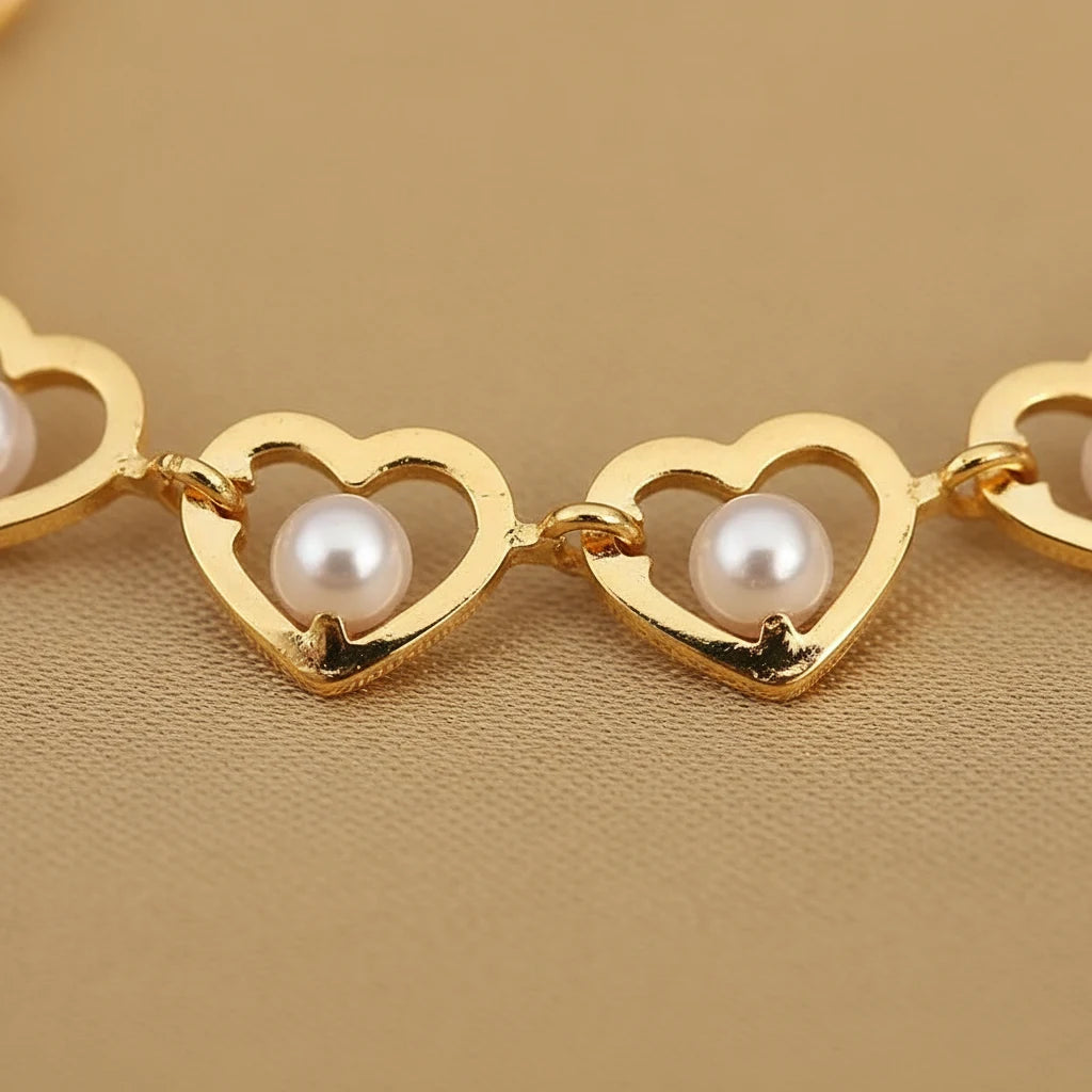 Macro shot of the Golden Pearl Heart Chain Bracelet showing each open gold heart cradling a luminous white pearl against a warm beige background, emphasizing the bracelet’s fine craftsmanship | Oria Jewel