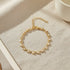 Golden Pearl Heart Chain Bracelet laid in a perfect circle on a neutral linen surface, softly lit to showcase the repeating heart-and-pearl design and delicate chain extender | Oria Jewel