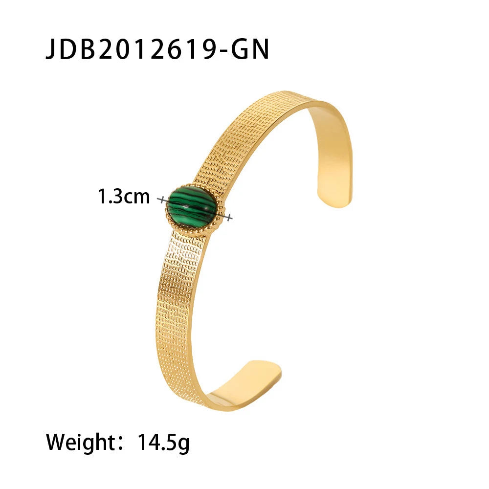Studio product image on a white background showing the Green Gemstone Cuff Bracelet laid flat with measurements indicating a 1.3 cm oval stone and 14.5 g weight, highlighting the slim open-band silhouette and textured gold finish | Oria Jewel