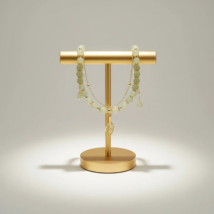 Studio shot of Jade Leaf adjustable charm bracelet hanging in two layers from a gold display stand, showcasing the delicate leaf charm | Oria Jewel