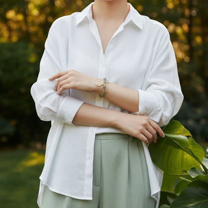 Jade Leaf adjustable charm bracelet styled on a woman in a white shirt and green trousers, standing among lush garden leaves | Oria Jewel
