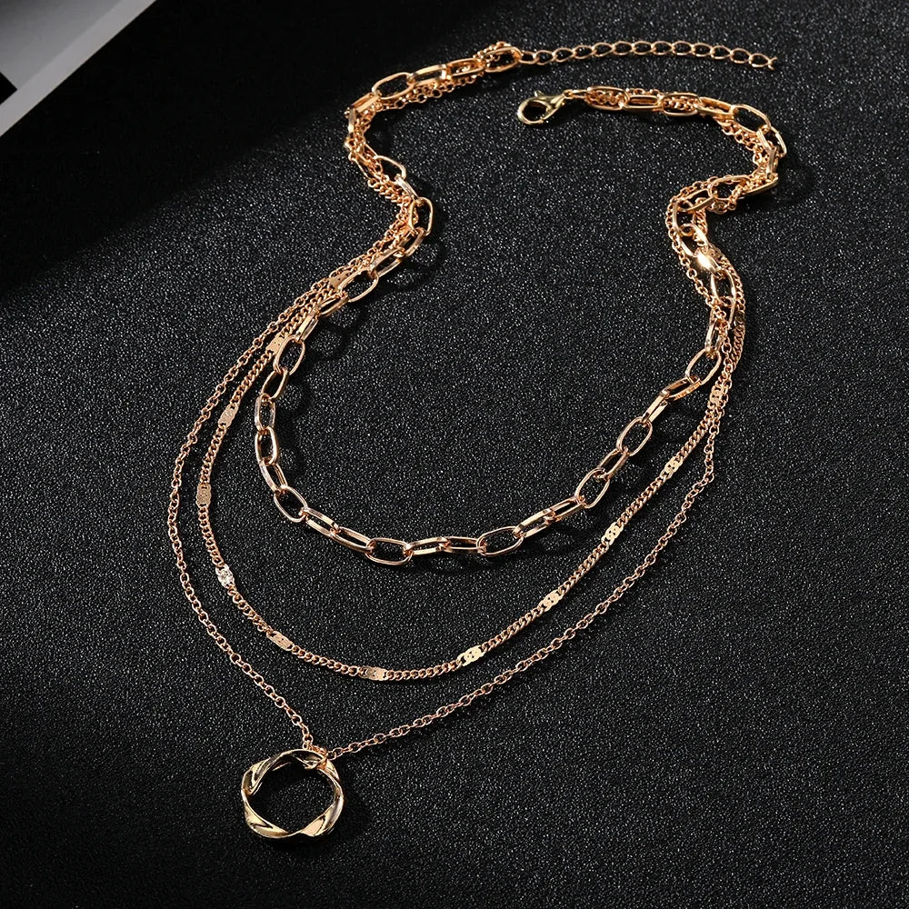 Layered Choker Necklace in gold displayed on black surface highlighting modern link, chain, and twisted pendant layers | Oria Jewel