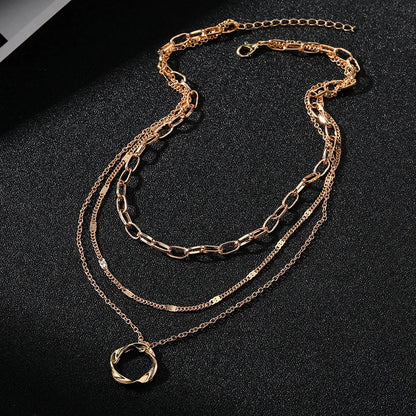 Layered Choker Necklace in gold displayed on black surface highlighting modern link, chain, and twisted pendant layers | Oria Jewel
