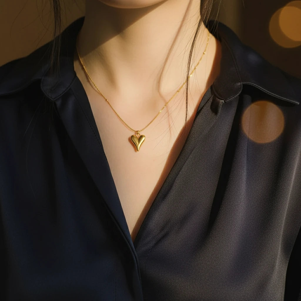 Woman wearing a Love Heart Pendant Necklace with a dark satin blouse, softly lit for an elegant look | Oria Jewel