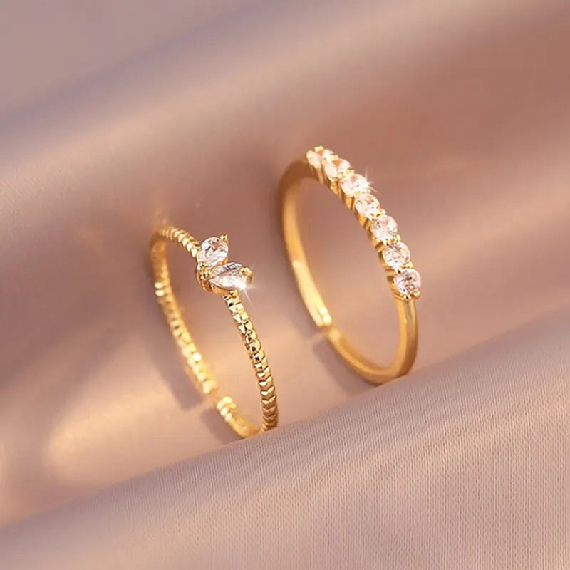 Luna Dainty Stack Ring Set styled on soft satin fabric, close-up of the two delicate gold stacking rings with a marquise crystal accent and a half-eternity row of round stones | OriaJewel
