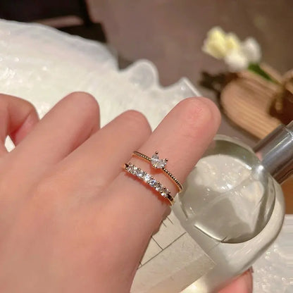 Luna Dainty Stack Ring Set worn stacked on the finger beside a clear perfume bottle, showing the dainty gold bands and sparkling stones in a cozy vanity-style scene | OriaJewel