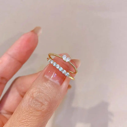 Luna Dainty Stack Ring Set held between fingers in a macro shot, highlighting the stacked look of the crystal row band and the marquise accent ring with a glossy manicure | OriaJewel