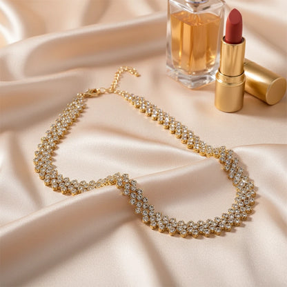 Luxury Rhinestone Chain Choker in gold tone displayed with perfume and lipstick on soft beige satin fabric | Oria Jewel