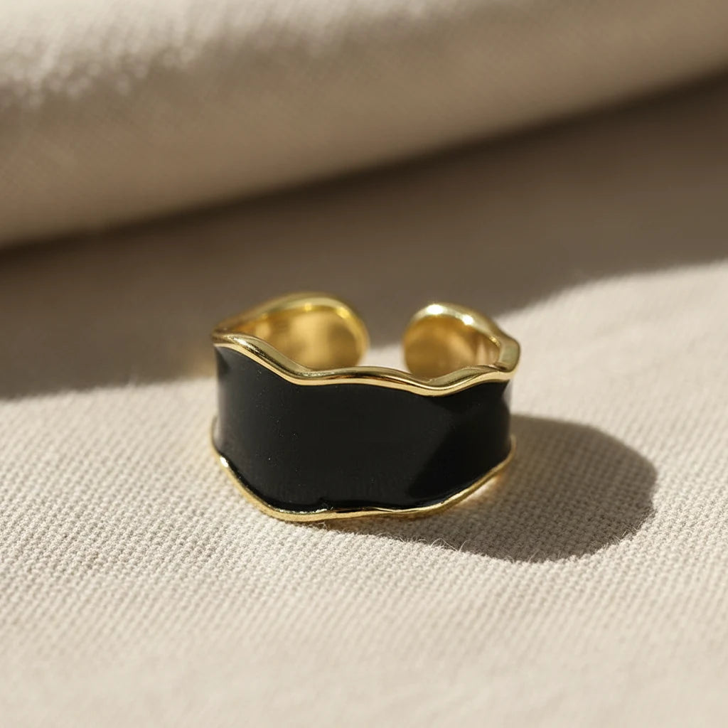 Midnight Black Open Wave Ring macro close-up on textured beige fabric, shiny black wave band framed with gold-tone edging under warm natural light | OriaJewel