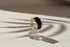 Midnight Black Open Wave Ring on a clear ring stand with dramatic window-shadow lines, black glossy open wave band with gold-tone trim | OriaJewel
