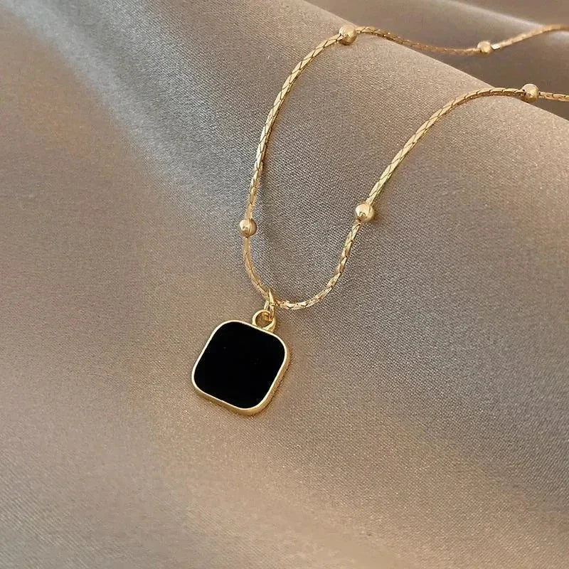 Minimalist Square Pendant Choker featuring a gold chain with a black square pendant on a soft fabric background | Oria Jewel