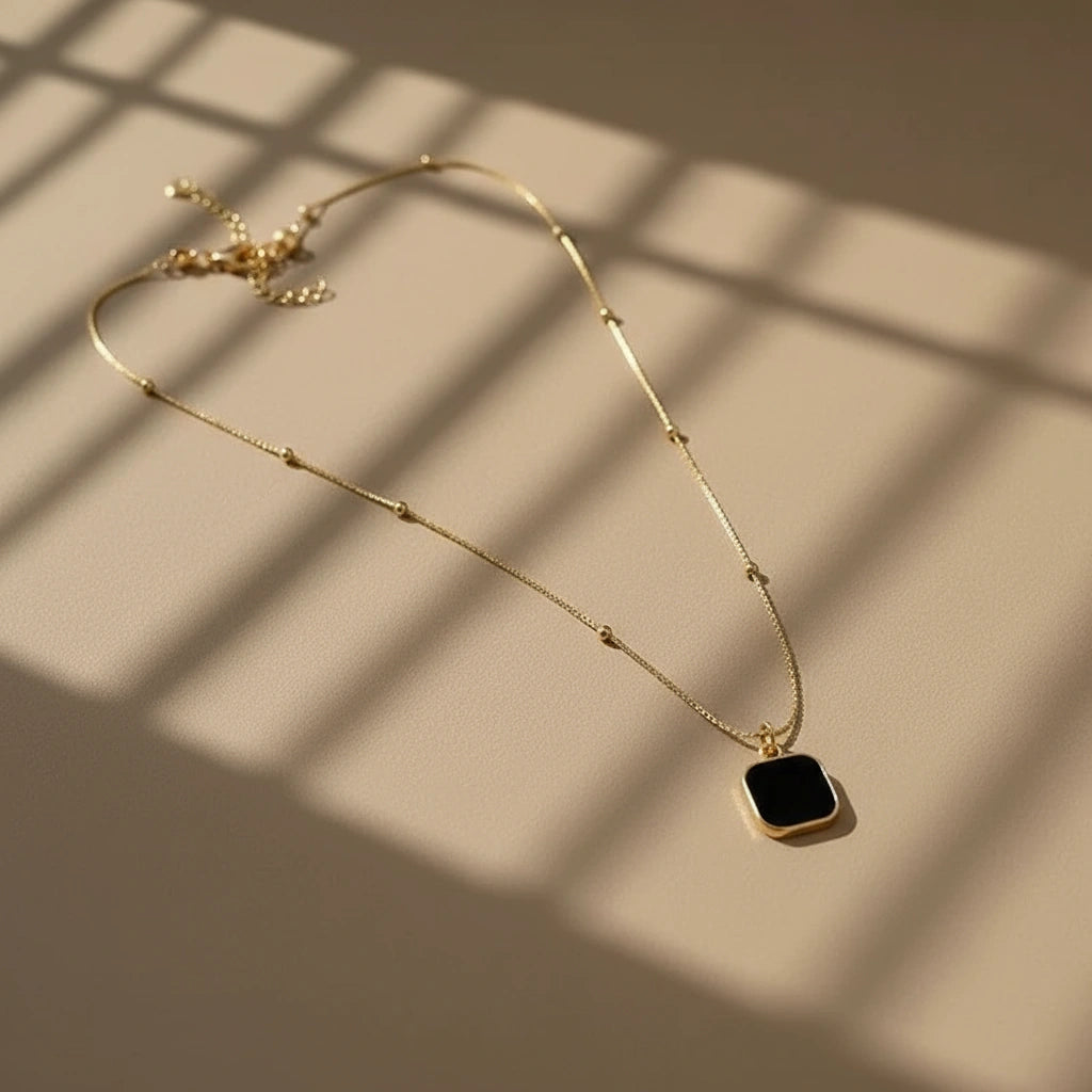 Minimalist Square Pendant Choker featuring a gold chain and a black square pendant on a light surface with shadows | Oria Jewel