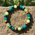 Close-up of the Money Attraction Tigers Eye Bracelet on a rough stone surface outdoors, with sunlight emphasizing the natural patterns in the tiger’s eye and malachite beads | Oria Jewel