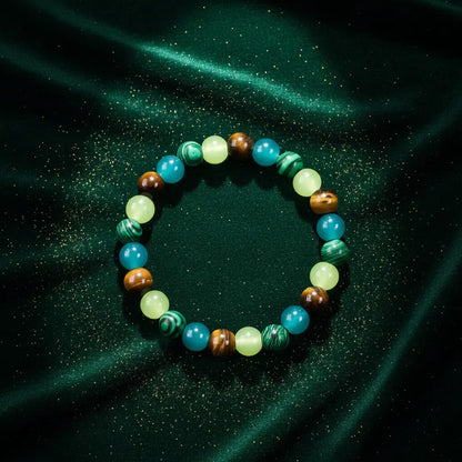 Money Attraction Tigers Eye Bracelet styled on deep emerald green satin sprinkled with fine golden glitter, giving a luxurious abundance and prosperity feel | Oria Jewel