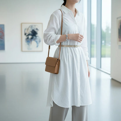 Gallery visitor in a white shirt dress and crossbody bag, posing in front of artwork with the Moonstone Glow Charm Bracelet as her subtle statement piece | Oria Jewel