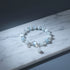 Moonstone Glow Charm Bracelet displayed on a cool marble surface, spotlighting the translucent blue beads and reflective moonstone centerpiece | Oria Jewel