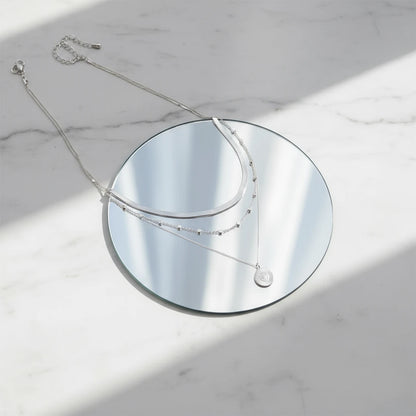 Multi Layer Silver Circle Chain Necklace showcased on round mirror with silver reflection in daylight | Oria Jewel