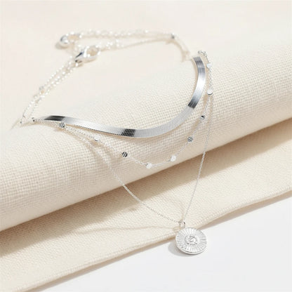 Multi Layer Silver Circle Chain Necklace displayed on soft cream fabric showing detailed layered chains and circle pendant | Oria Jewel