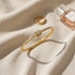 Lifestyle flat-lay of the Pavé Stackable Gold Bangle on soft beige fabric next to a matching gold ring and a perfume bottle, styled to show how easily the bangle stacks with other delicate accessories | Oria Jewel