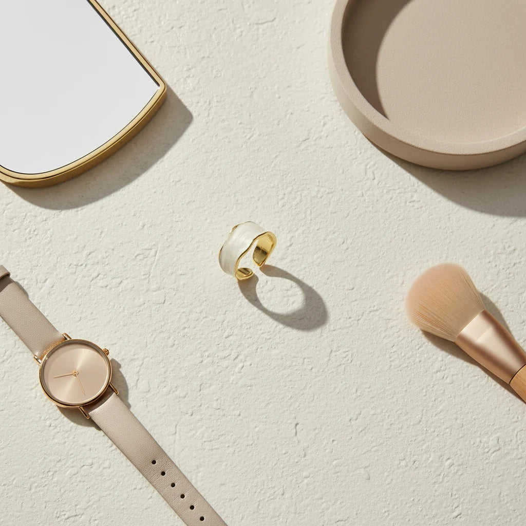 Pearl White Open Wave Ring flat-lay on a textured neutral surface with a watch, mirror edge, ceramic tray, and makeup brush, highlighting the wide pearl-white wave band and gold-tone interior | OriaJewel
